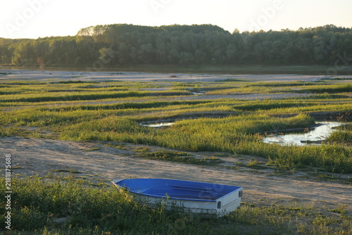 Foto Small blue boat left aground on the dried bed of the Danube River with remnant p