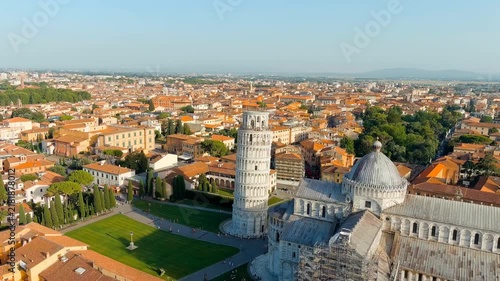 Pisa, Italy. The Leaning Tower and Pisa Cathedral in Piazza dei Miracoli, aerial drone view over the marble complex and terracotta rooftops at summer evening light. Drone footage