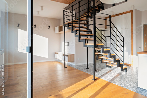 Modern interior with staircase in a design house with wiiden floor, light and space. Construction of stairs with metal railings. New apartment and indoors architecture.