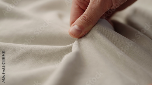 man manually check ivory color cotton fabric for clothing with hands