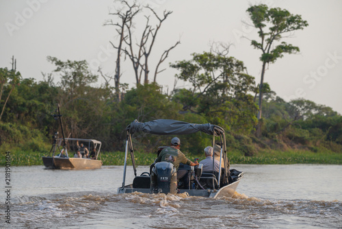 Tour boats heading upriver at dawn in the Pantanal of Brazil