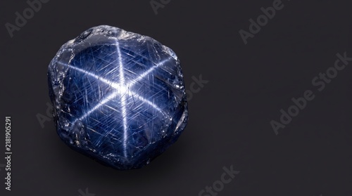 Blue star sapphire gemstone showing asterism effect on a dark background
