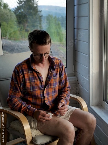 Fotografía A male patient with multiple sclerosis holding a syringe and giving himself an injection in the leg