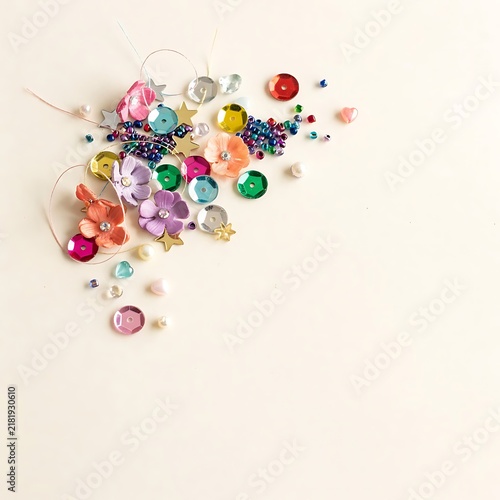 Colorful collection of assorted craft supplies including beads sequins and flowers on a light background