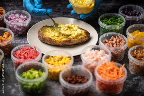 Baked potatoes with cheese, herbs, meat and butter. Copy space background. BBQ or steakhouse side dish favorite with tomato beans, cheddar cheese, bacon.