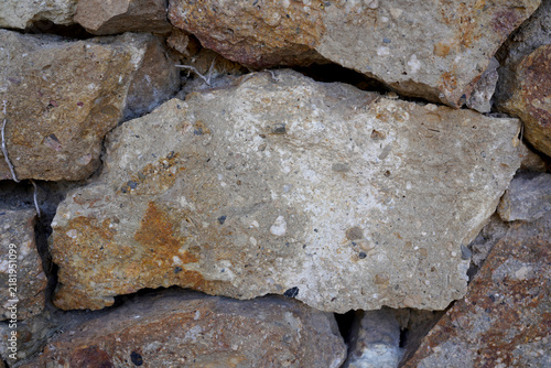 Close up texture of rough natural stone wall with varied colors and irregular shapes in Barcelona