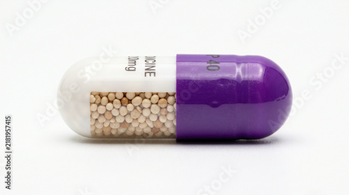 Single purple and white medical capsule pill isolated on a clean white background