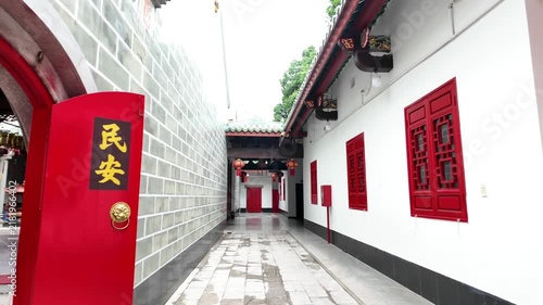 Traditional moon gate entrance and red wooden lattice doors at a historic Chinese temple in Cholon, Ho Chi Minh City, Vietnam