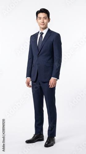Full body studio portrait of handsome Asian businessman in formal navy blue suit isolated on white background.