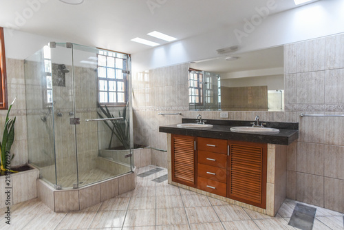Modern Bathroom with Shower and Double Vanity: A spacious and contemporary bathroom features a glass-enclosed shower stall, a sleek double vanity with granite countertops, and tiled walls and floors.
