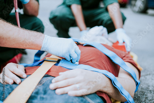 Bild auf Leinwand Paramedics restraining an injured white male on the ground during emergency aid