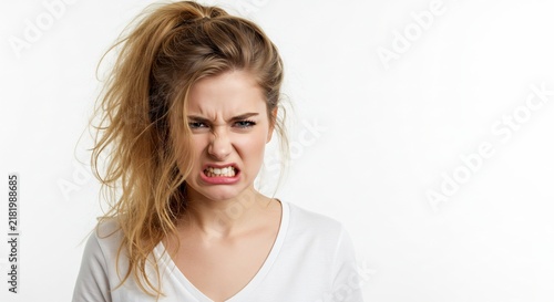 Disgusted Woman's Grimace: A young woman recoils with a look of pure disgust, her face contorted in a grimace of aversion, her blonde hair pulled into a messy ponytail.