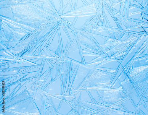 Ice frozen in intricate patterns of delicate crystals in sparkling blues. Det...