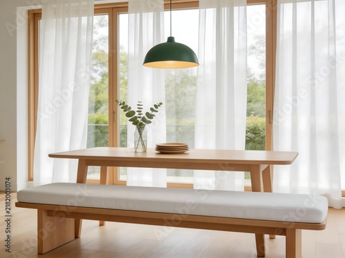 Modern wooden dining table with bench and green pendant light in sunlit room with sheer curtains