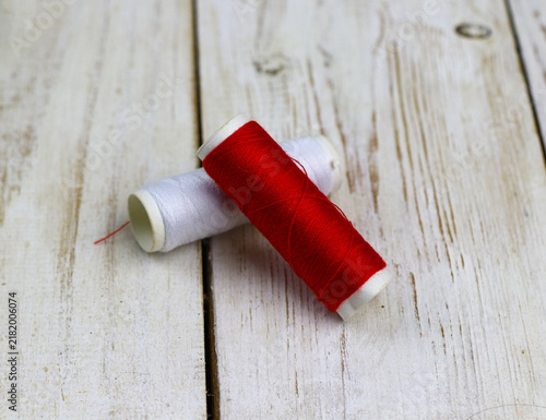 Obraz na płótnie red and white sewing thread on a rustic wooden table.