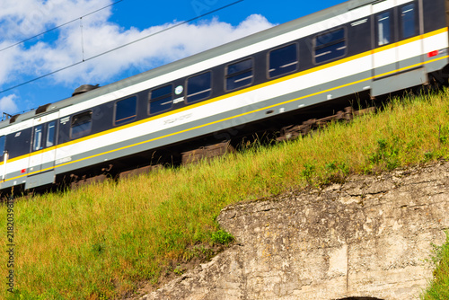 Bild auf Leinwand Modern passenger commuter train speeding along elevated track against blue sky,