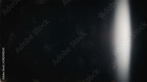 Dark black vintage film grain texture with vertical white light leak, dust and subtle scratches. Cinematic analog overlay for retro photography, grunge backgrounds and aged effects
