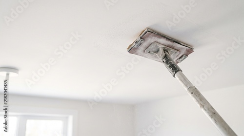 Drywall ceiling sanding with a pole sander during home renovation project