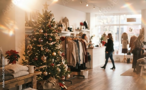 Festive boutique clothing store interior decorated with a glowing Christmas tree for holiday shopping with adult women customers