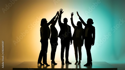 Group of professional business colleagues standing together in a line lifting hands up to celebrate successful teamwork and collective corporate achievement in an office environment with warm