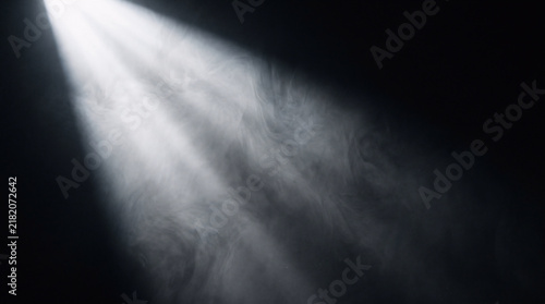 a wide powerful white spotlight beam projecting diagonally through the darkness