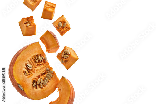 Fresh orange pumpkin slices and cubes falling downward on a white surface isolated on a transparent background