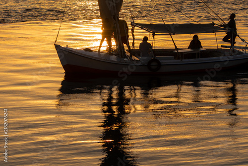 Fotografie Felucca and passenger silhouettes on the Nile at sunset in Luxor