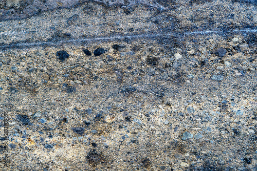 Canvas Print Rough dark gravel sand texture background with volcanic rock elements, coarse weathered stone surface close-up