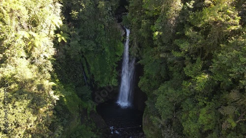 Aerial footage of Cidadap Waterfall Surrounded by Wild Banana Trees and Dense Tropical Vegetation During Morning in Indonesia. Forest and the Flowing Cascade Create Vibrant Nature in the Wilderness.