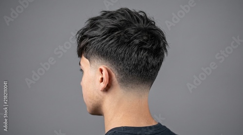 Modern textured fade haircut, stylish mens short hairstyle with tapered back, professional barber shop grooming on gray background