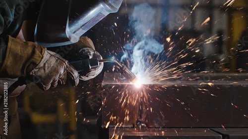 Industrial metal welding process with bright sparks flying in a professional workshop.