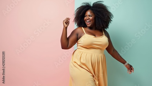 Full body African woman of plus size model dancing on pastel background