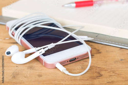 mobile phone, earphone and notebook planner arrangement flat lay style on background wooden 