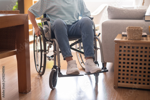 Person navigating a wheelchair through a modern living room, representing independence and accessible living for individuals with mobility disabilities within their home environment