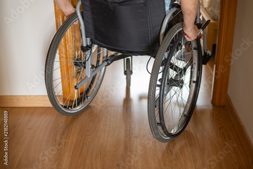 Person in wheelchair passing through a wooden doorframe, illustrating accessible housing design that supports independence, mobility and barrier-free living at home