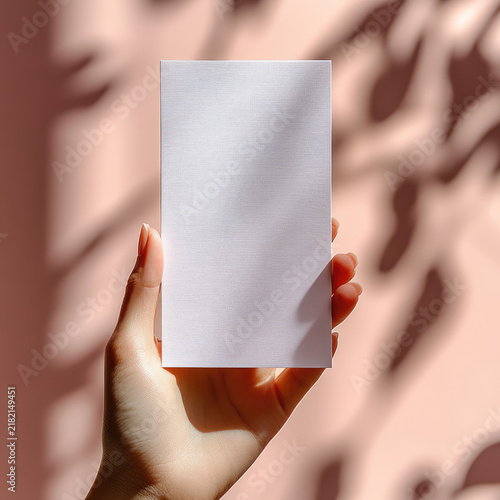 The image features a person holding a rectangular, blank, white card or piece of paper vertically in their hand