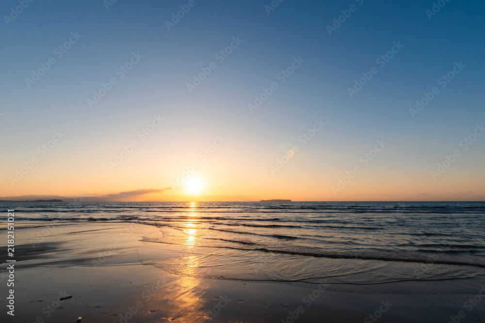 Fototapeta premium Sunset over the ocean with golden reflections on a beach in Fukuoka, Japan