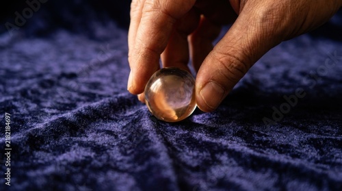 Fingers Picking Up Transparent Glass Marble on Rich Blue Velvet