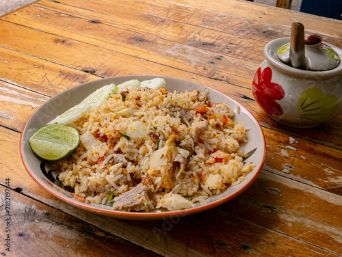 Bild auf Leinwand Thai Pork Fried Rice with Cucumber Slices and Lime on Rustic Wooden Table, Homes
