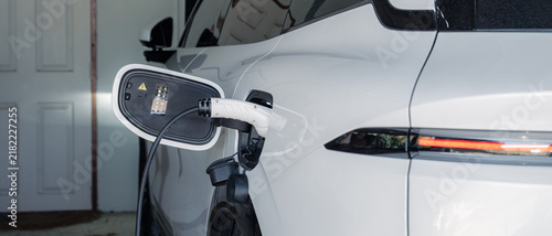 Foto Person plugging in EV charging cable to white electric vehicle for sustainable energy transport