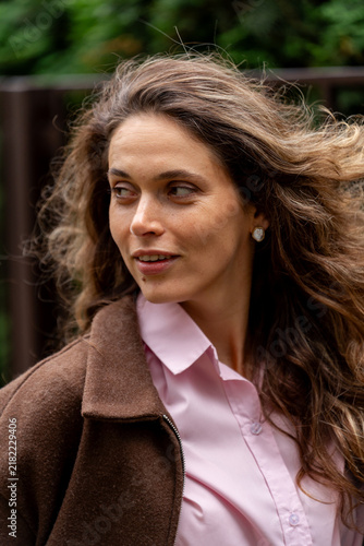 Close up of beautiful young woman with flying curly hair looking away