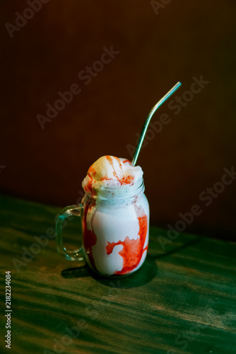 Bild auf Leinwand Strawberry milkshake float with vanilla ice cream scoop and syrup drip in mason