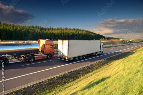 A truck on a highway drives through a wide landscape, transporting goods