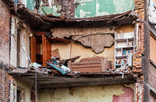A destroyed apartment exposed by a missile strike in Kyiv, with a damaged sofa, furniture and books amid debris and structural destruction