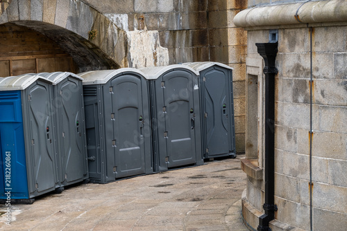 Quadro su tela Row of Portable Toilets Beside a Stone Building