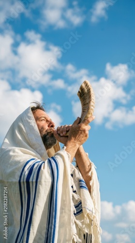 Religious jewish man wearing a tallit prayer shawl looking up to the blue sky with clouds in a spiritual moment