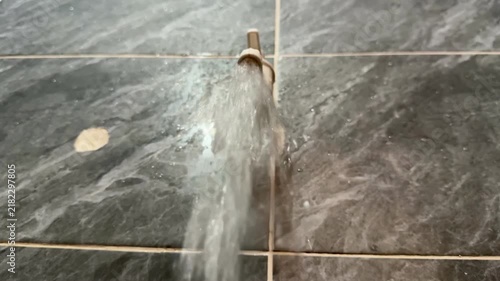 Water Running From Plastic Tap Against Grey Marble Tile Wall