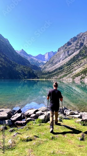 Hiker walking towards mountain lake with scenic reflections and peaks- Lake Gaube- vertical video