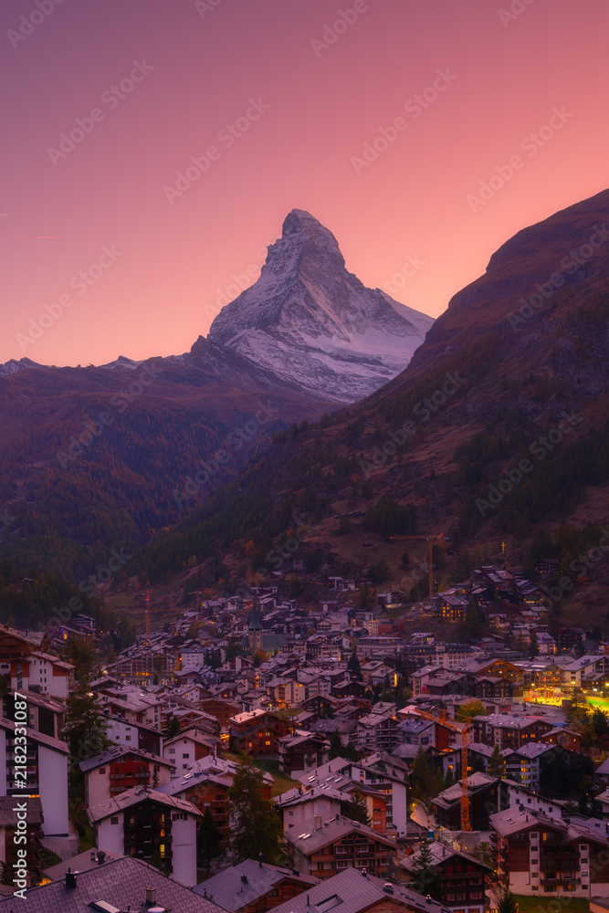 Obraz premium Vertical photo. Sunset view over the town of Zermatt with Matterhorn mountain in the background. Evening light illuminates Swiss alpine village and peak.