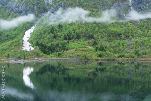 Waterfall in fjord lake with reflection Norway